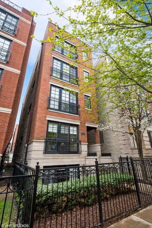 Front view of a multi-story brick building with large windows and balconies.