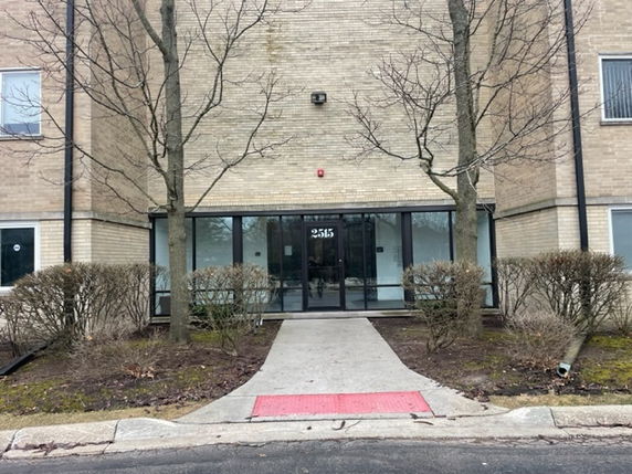 Front view of a building with glass entry doors and brick exterior.