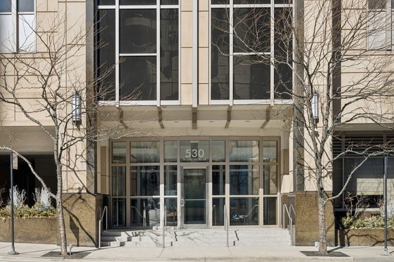 Front view of an apartment building entrance with glass doors and windows.