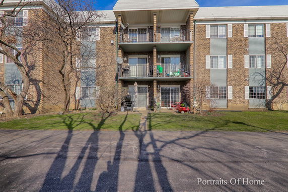 Front view of a multi-story brick apartment building with balconies.