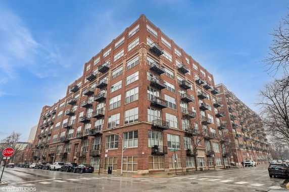 Front view of a multi-story brick apartment building with balconies.