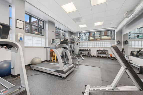 Indoor gym area with exercise equipment including treadmills and weight racks.