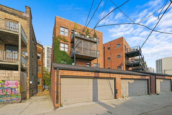 Front view of a brick multi-story building with balconies and ivy.