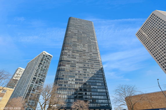Front view of a tall glass-covered skyscraper against a blue sky.