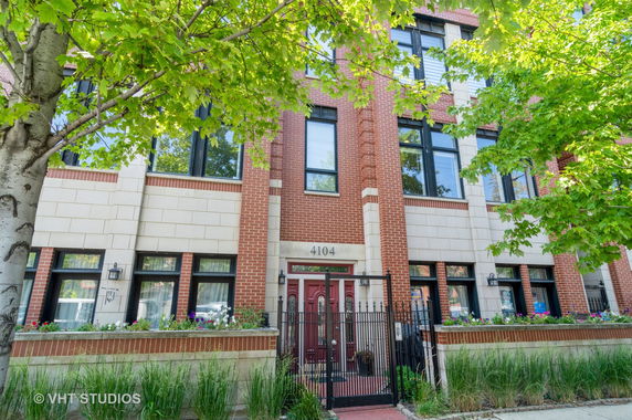 Front view of a brick multi-story building with large windows and a gated entrance.