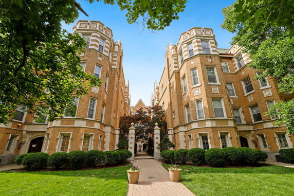 Front view of a large brick residential building with decorative stone elements and an archway entrance.
