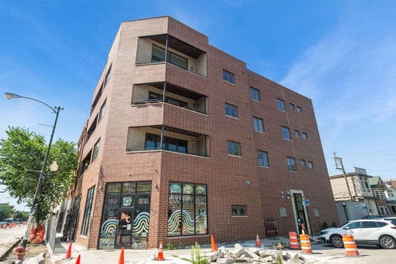 Front view of a multi-story brick building with commercial space on the ground floor.