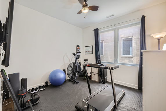 Indoor gym area with exercise equipment including a treadmill, exercise bike, weights, and a yoga ball.