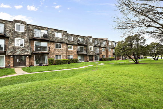 Front view of a multi-story brick apartment building with balconies.