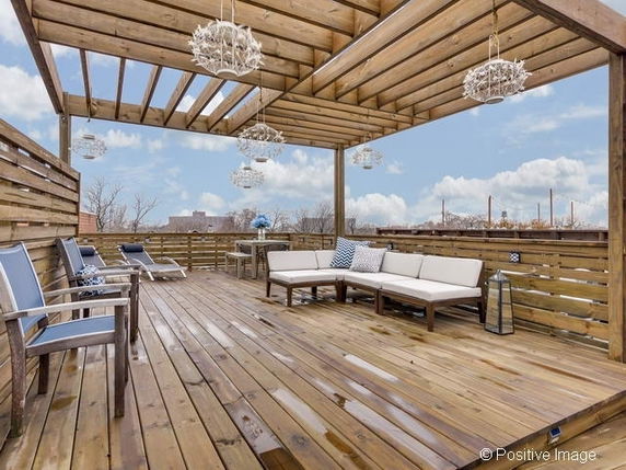Rooftop with wooden decking and seating area under a pergola.