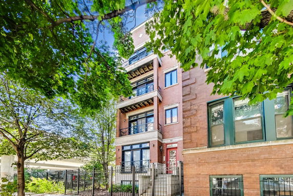Front view of a multi-story brick apartment building with balconies.