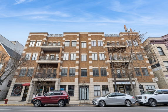 Front view of a multi-story brick building with balconies and windows.