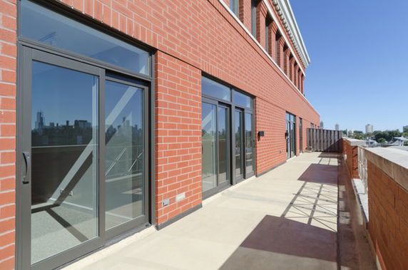 Exterior view of a brick building with large glass doors opening to a balcony.