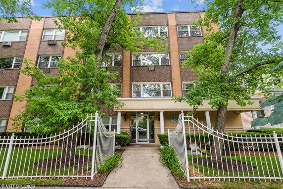 Front view of a multi-story apartment building with a gated entrance.