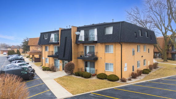 Front view of a three-story brick apartment building with balconies.