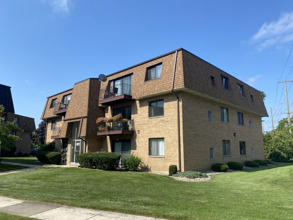 Front view of a multi-story brick apartment building with balconies.