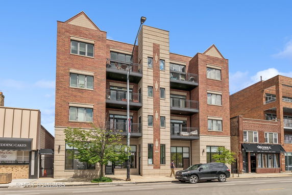 Front view of a multi-story brick apartment building with balconies.