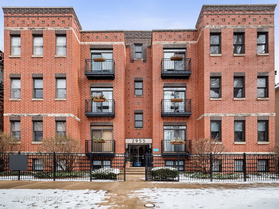 Front view of a multi-story brick apartment building with balconies.
