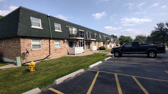 Front view of a two-story apartment building with brick facade and dark green roof.