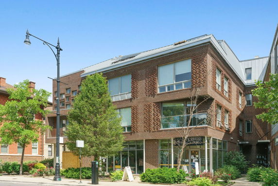 Front view of a modern multi-story brick building with large windows.