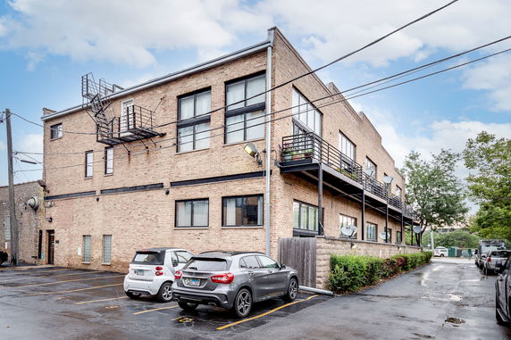 Side view of a multi-story brick building with parking area.