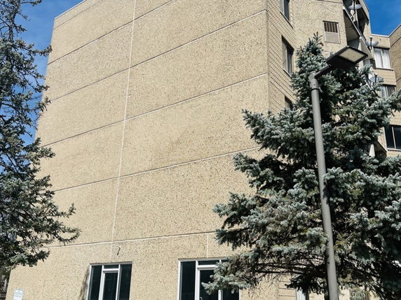 Front view of a multi-story building with a textured facade and several windows.