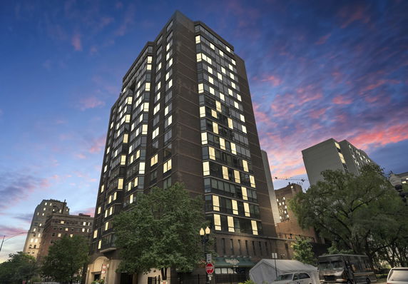 Front view of a multi-story building with numerous windows, set against a colorful evening sky.