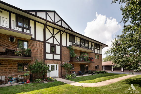 Front view of a multi-story building with brick and wood paneling.