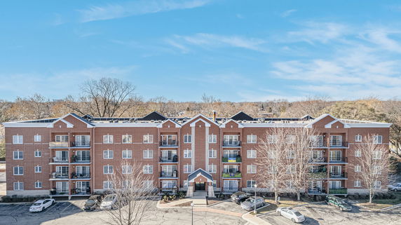 Front view of a multi-story brick apartment building with balconies.