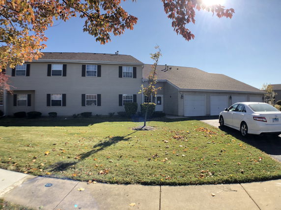 Front view of a two-story house with multiple garages and a car parked outside.