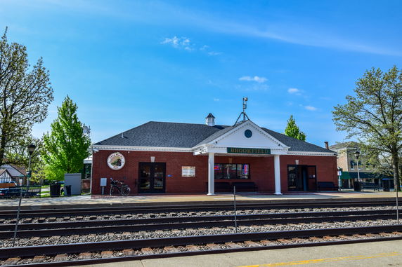 Front view of a brick train station building with a peaked roof and columns.