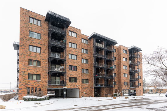 Front view of a multi-story brick apartment building with balconies.