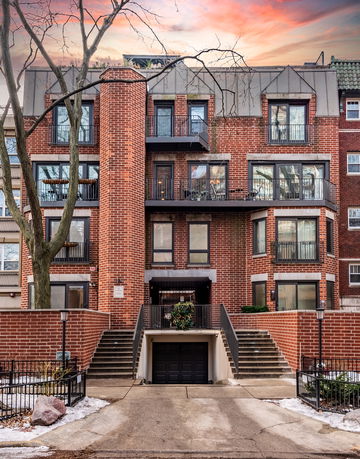 Front view of a multi-story brick building with balconies and a central entrance.