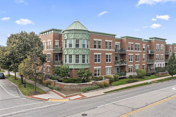 Front view of a brick building with green rooftops and multiple windows.