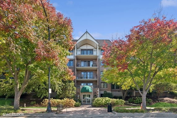 Front view of a multi-story residential building with balconies and a green awning entrance.