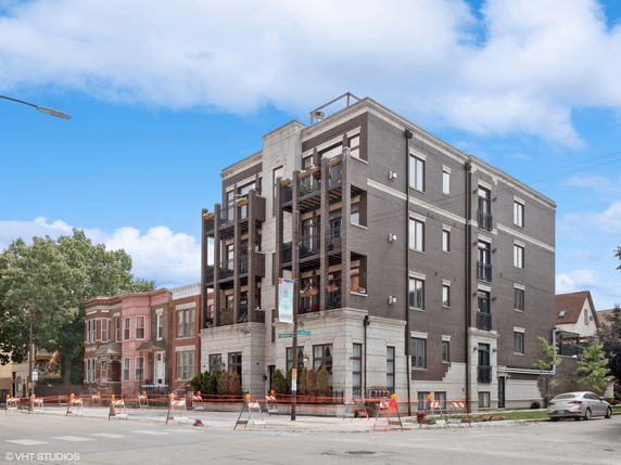 Front view of a four-story residential building with balconies and brick exterior.