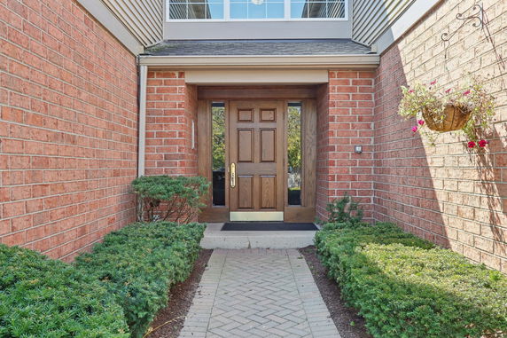 Entrance view of a house with a wooden front door and brick walls.