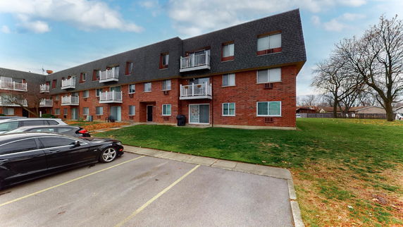 Front view of a three-story brick apartment building with balconies.