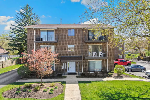 Front view of a three-story brick apartment building with balconies and a central entrance.