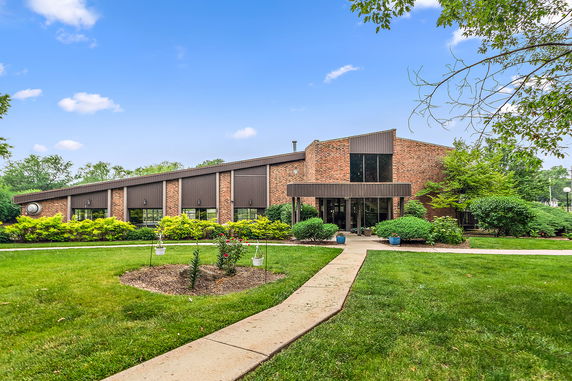 Front view of a brick building with a modern entrance and surrounding greenery.