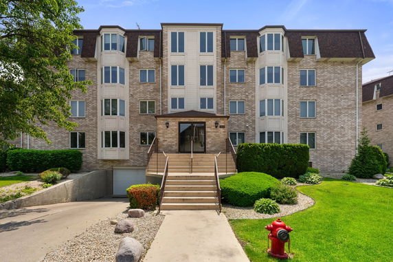Front view of a multi-story apartment building with a central entrance and symmetrical design.