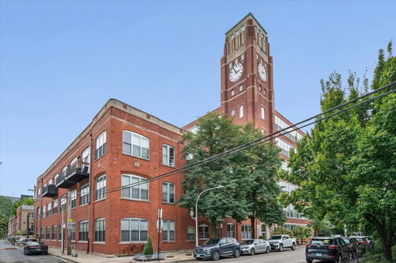 Front view of a multi-story brick building with a prominent clock tower.