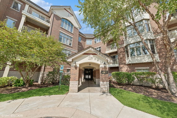 Front view of a multi-story brick building with balconies and entrance canopy.