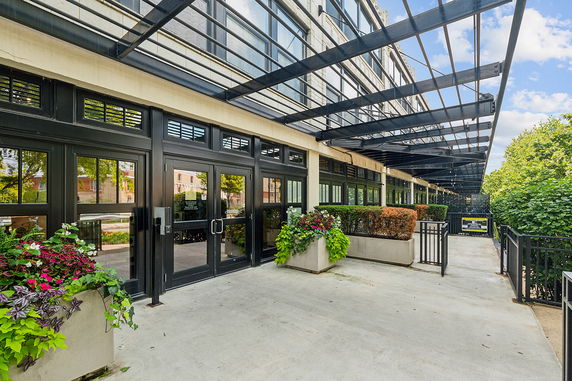 Front view of a building with glass doors and an overhead pergola.