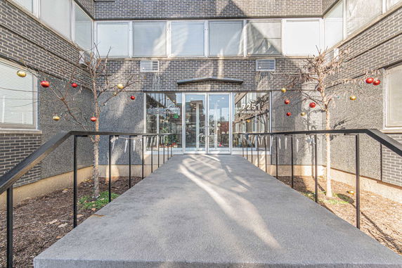 Front view of a condominium building entrance with decorated trees.