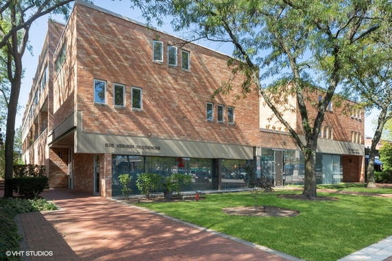 Front view of a multi-story brick residence building with large windows.