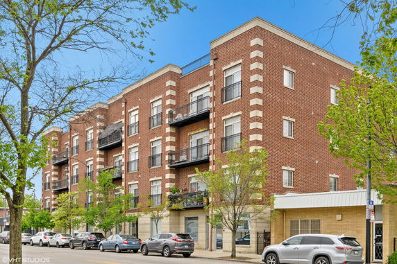 Front view of a multi-story brick residential building with balconies.