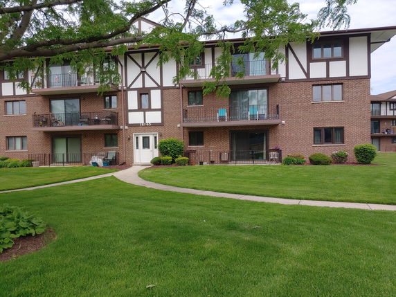 Front view of a multi-story brick apartment building with balconies.
