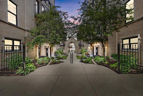 Front view of a multi-story building with a central walkway and landscaped entrance.