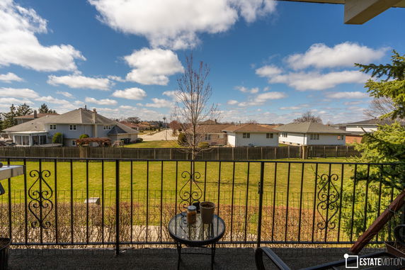 Panoramic view from a balcony showing neighboring houses and a spacious backyard.